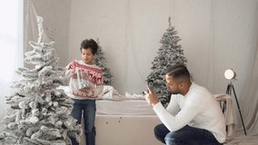 African American man films son decorating tree at home and saying hi, father takes smartphone photo of child at Christmas - Powered by Shutterstock - Get 15% off with code: PIKWIZARD15