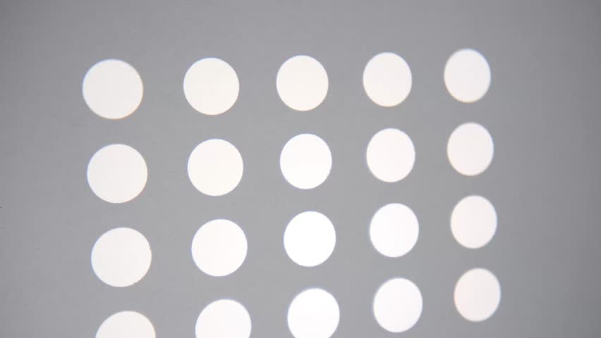 Bright white circular light spots form a clean geometric pattern on a smooth light grey surface, creating a minimalist abstract background.