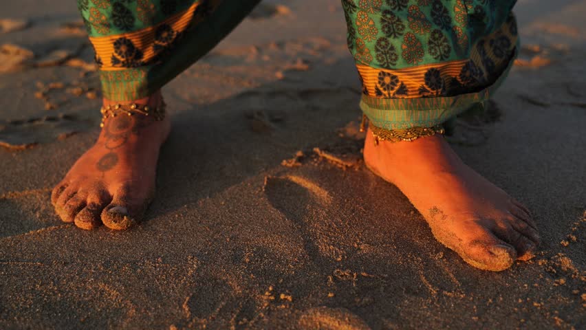 Bare Feet with Henna and Anklets on Sandy Beach at Sunset