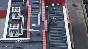Aerial view of an industrial rooftop with ventilation ducts, exhaust units, and solar collectors beside an urban alleyway with modern residential balconies in Vilnius, Lithuania. - Powered by Shutterstock - Get 15% off with code: PIKWIZARD15