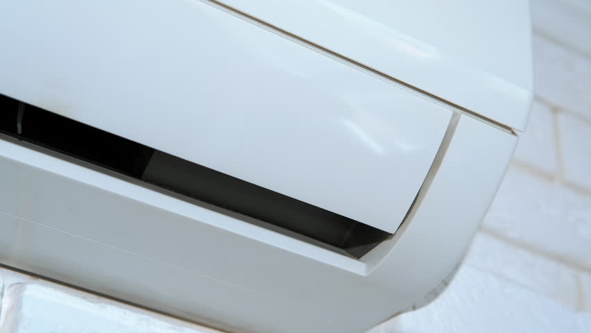 Air conditioner inverter working. A view of opened air conditioner inverter working on the white wall in the room