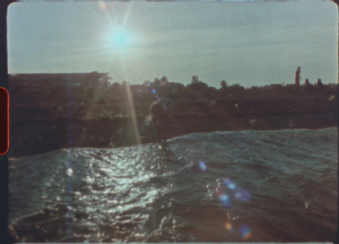 Young girl picking and throwing stones into the sea on retro super 8mm vintage film