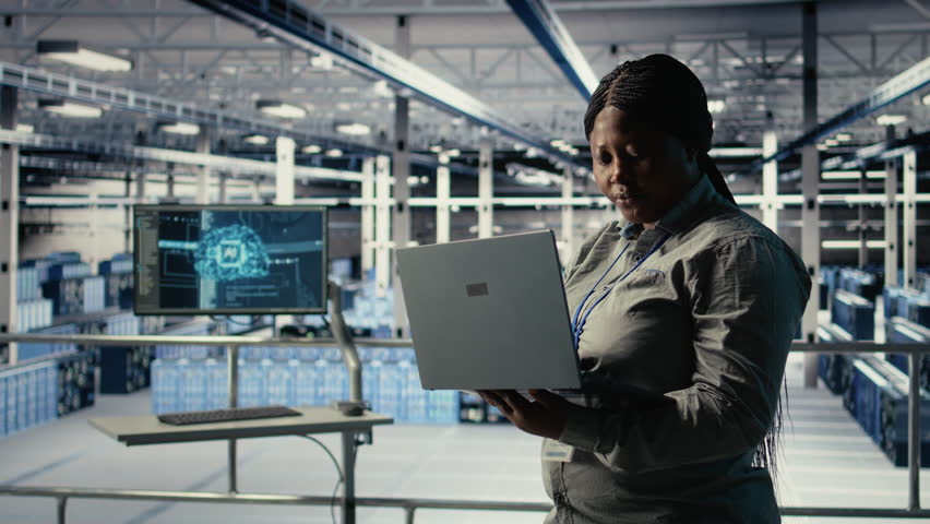 Data center admin monitors deep learning process with laptop, reviewing operational metrics. African american woman using device to review neural networks reports during inspection, camera A - Powered by Shutterstock - Get 15% off with code: PIKWIZARD15