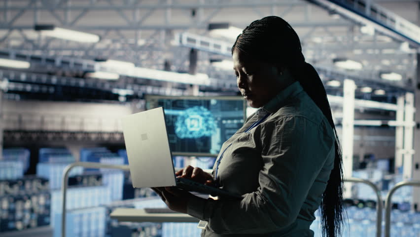 Data center supervisor on industrial platform working to improve AI rigs processing speed. African american server hub manager overseeing gear supporting artificial intelligence workloads, camera B