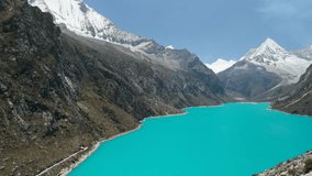 A spectacular aerial shot pans alongside a steep mountain, revealing the vast, vibrant turquoise waters of Laguna Parón and the snow-capped peaks of the Cordillera Blanca in Peru. - Powered by Shutterstock - Get 15% off with code: PIKWIZARD15