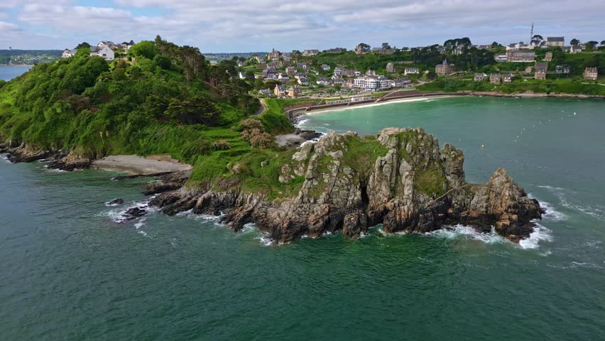 Pointe du Chateau rocky headland and Perros-Guirec coastal town, Brittany, France. Aerial drone ascending