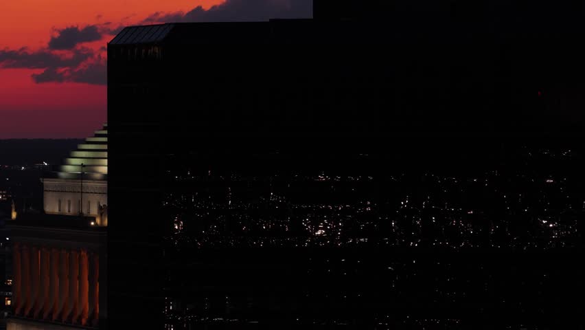 Drone shot of St. Louis skyline with glass building foreground, revealing the circuit courthouse at sunset. Bright orange sky and golden hour light over Missouri’s iconic cityscape.