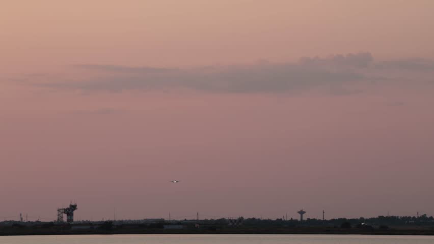 Cagliari, Sardinia, Italy A commercial airliner lands at the Cagliari Elmas Airport at sunset.