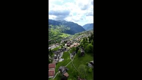 Vertical drone shot rising above Grindelwald’s alpine meadows, revealing snow-capped peaks and the picturesque Swiss village under a bright summer sky. - Powered by Shutterstock - Get 15% off with code: PIKWIZARD15