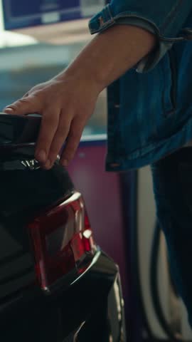 A person inspects the rear of a sleek car, engaging with its design elements, while enjoying a warm afternoon at a bright automotive showroom