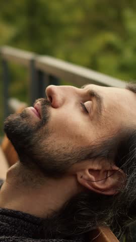 Engulfed in tranquility, a man breathes deeply as he meditates outdoors, surrounded by nature's lush greenery, embodying inner peace and relaxation