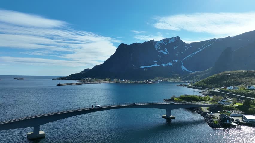 Reine bridge over Reinefjorden with traffic, Reinebringen mountain and village in Lofoten spring