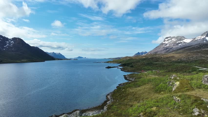 Road E10 runs along Austnesfjorden towards Svolvaer with mountains, fjord, and ocean horizon in view