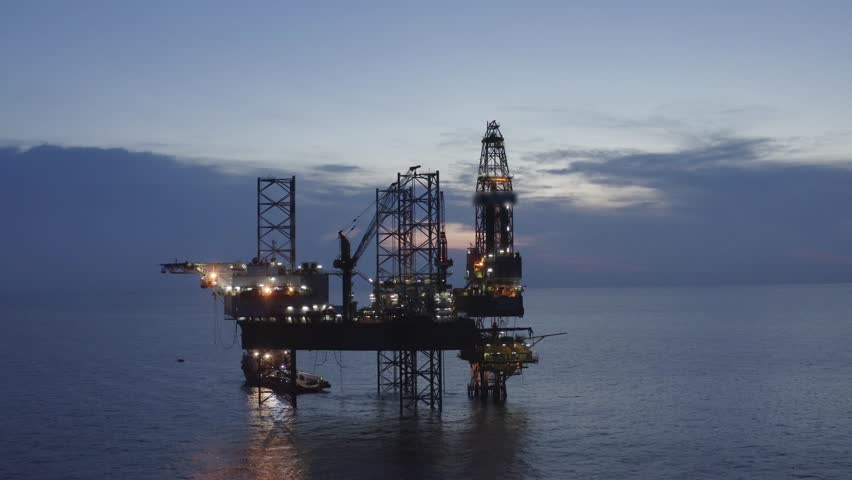 Areal top view of offshore jack up rig and offshore platform during sunset for oil and gas exploration and production. 