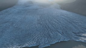 Aerial view of a vast, textured glacier flowing into calm waters, a stark contrast of icy blues and muted grays, creating a serene yet powerful landscape, Hornafjorður, Iceland. - Powered by Shutterstock - Get 15% off with code: PIKWIZARD15