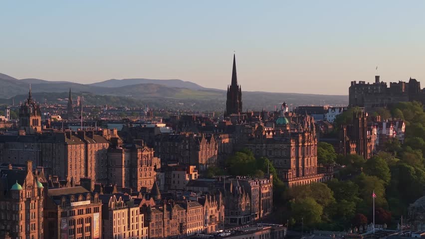 Drone orbits Edinburgh’s historic Old Town, revealing the iconic Edinburgh Castle in the background during golden hour for a cinematic cityscape