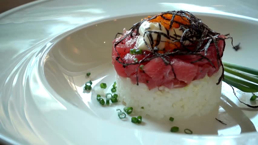 Delicious tuna tartare with rice and seaweed on a white plate isolated