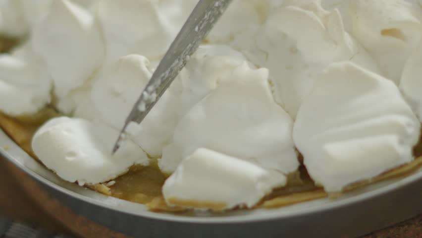 Top View of Meringue Cracking in Slow Motion as Knife Gently Cuts Through to Soft Lemon Curd Below. Close Up of Indulgent Sweet Homemade Dessert Food. High in Sugar and Flavour.