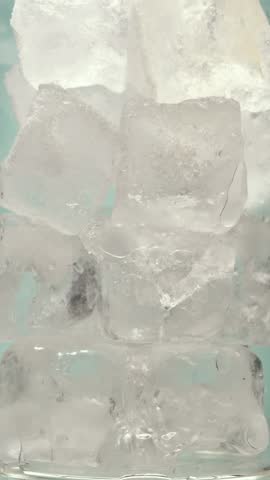 Sparkling amber drink cascades over ice cubes, bubbles rising in tall glass, refreshing summer thirst quencher captured in macro