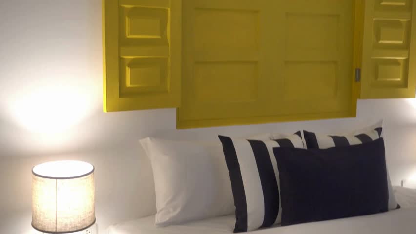 Bedroom interior with yellow window, pillows and lamp, a cozy and modern design