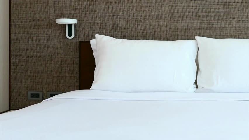 Close up of a comfortable bed with white linens and pillows in a hotel room