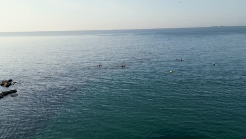 Aerial view of several kayaks and buoys scattered across the ocean