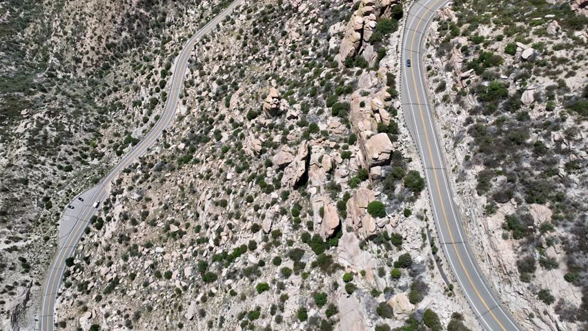 Aerial view of the winding road through the Santa Catalina Mountains, with scattered rocks and sparse vegetation, creating a rugged and textured landscape, Arizona, United States.