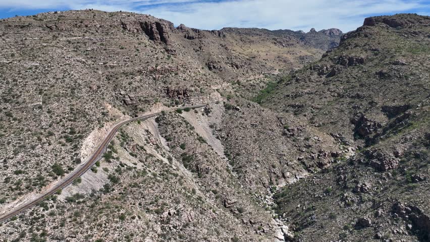 Aerial view of a winding road snaking through the rugged, arid mountains, showcasing the stark beauty and contrasting textures of the landscape, Summerhaven, Arizona, United States.