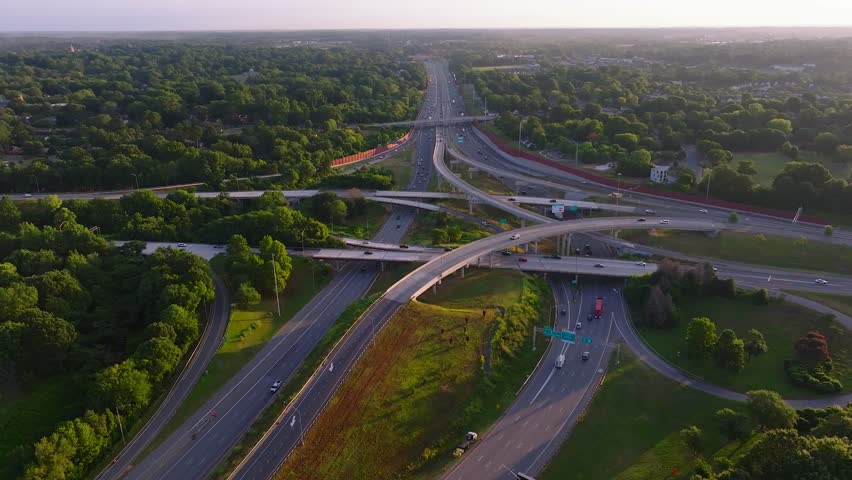 Aerial view of an intricate highway intersection surrounded by dense green trees and cars moving, Charlotte, North Carolina, United States.