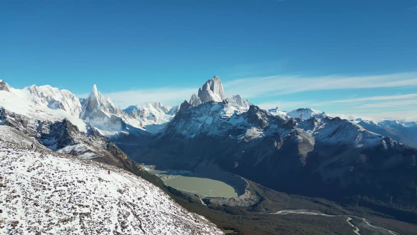 4K aerial of Laguna Torre with the iconic Fitz Roy and Cerro Torre in view. Clear skies reveal snowy summits and dramatic Patagonian landscapes.