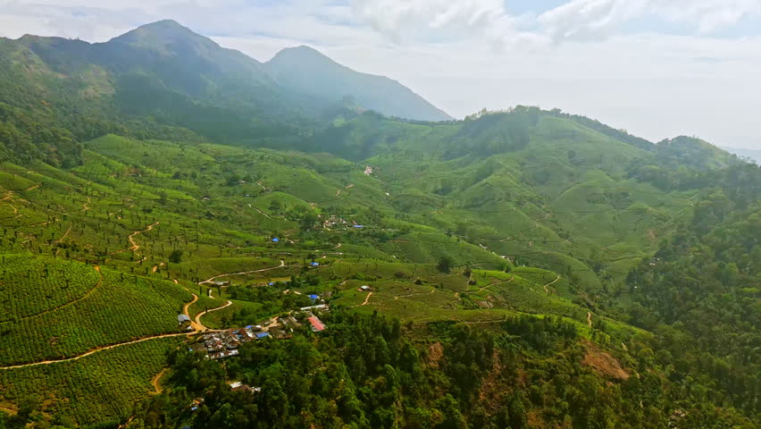 Panoramic drone shot overlooking a wide scenery of tea fields in Munnar, India