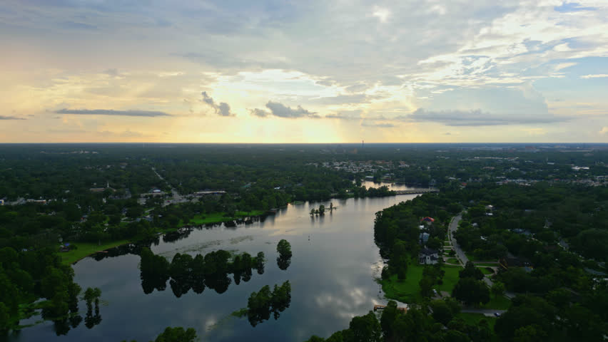 Aerial establishing over Hillsborough River with distant Tampa skyline under evening clouds reflection in water, panoramic of Florida suburb