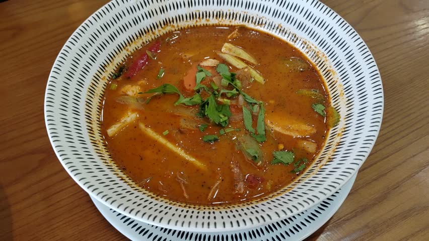 A bowl of mixed Tom Yum soup, a popular dish from Thailand. This spicy and sour dish is a favorite in Malaysia, known for its vibrant flavors and aromatic herbs.