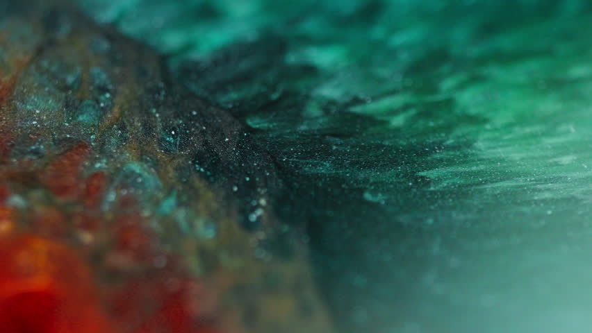 Macro view of green and orange glittery inks forming bubbles and wave-like patterns, resembling a snake skin texture.