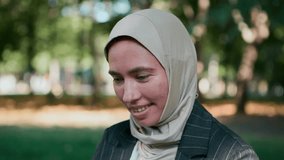 Muslim businesswoman in hijab sitting on grass with confident smile closing the laptop, taking break from work in park. Concept of leadership, career growth, and peaceful professional mindset. - Powered by Shutterstock - Get 15% off with code: PIKWIZARD15