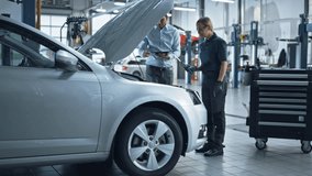 Auto Repair Shop: Manager Checks Tests on a Tablet Computer and Explains an Engine Breakdown to an Female Mechanic. Car Service Employees Inspect Car's Engine BayModern Clean Workshop. - Powered by Shutterstock - Get 15% off with code: PIKWIZARD15