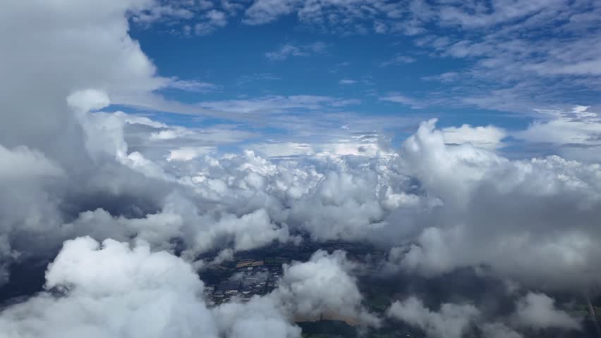 An immersive pilot’s view from the cockpit of a jet flying peacefully through white cottony cumulus clouds under a blue sky. Aerial ultra-realistic 4K shot.