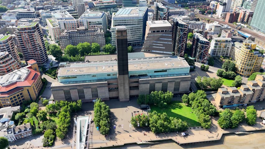 Sweeping aerial pan over Tate Modern, Millennium Bridge, and lush riverside gardens in central London. Captures vibrant Thames views, iconic architecture, and urban greenery in cinematic detail.
