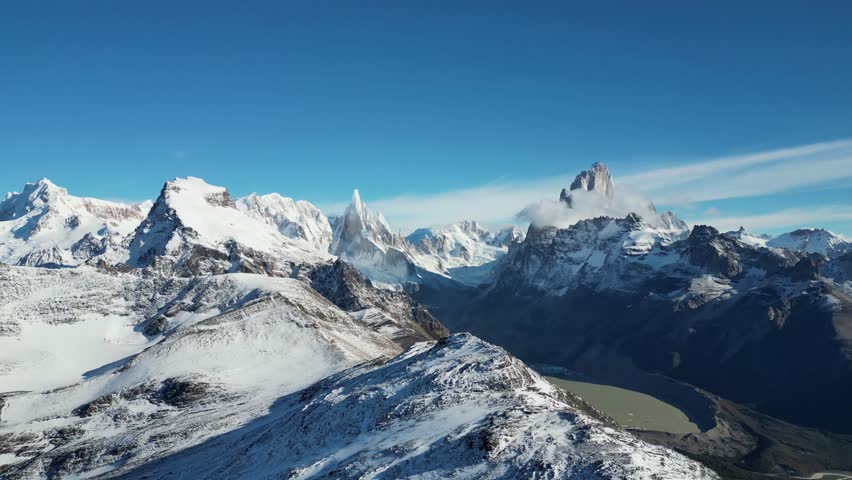 Drone panorama over Laguna Torre near El Chaltén. Majestic Fitz Roy and Cerro Torre peaks stand snow-covered beneath a cloudless sky in Patagonia’s rugged Andes.