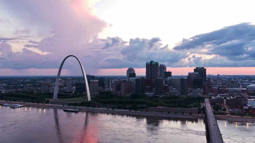 Hyperlapse shot of the St. Louis city skyline at sunset with storm clouds moving in. Rain can be seen in the background against the scenic pink sky.