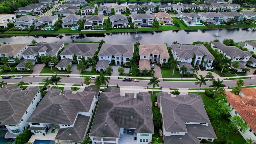 Aerial: residential area, lake and grey mansions during the day in Boca Raton, West Palm Beach, Florida, USA, establishing drone shot