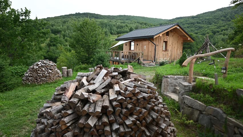 A Charming Rustic Wooden Cabin Nestled in a Lush Green Mountain Forest with Firewood.
