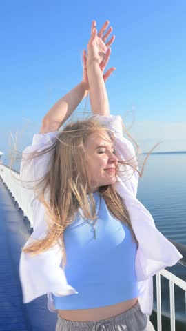 Beautiful blonde girl with hands up and loose hair on the deck of a ferry. Slow motion.