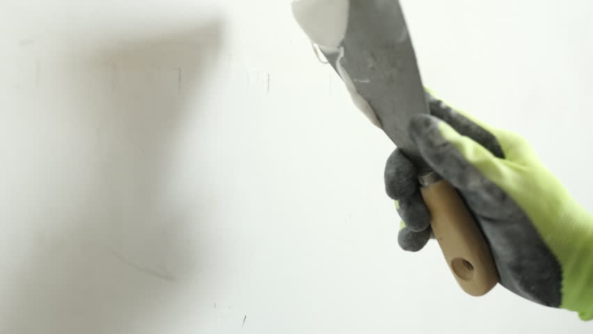 Worker Applying Wall Putty With A Spatula While Smoothing The Wall