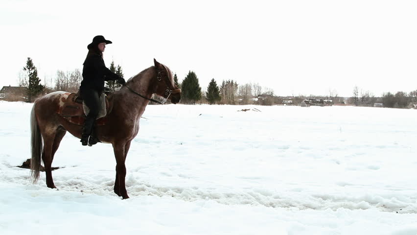 female cowboy rides a horse at a gallop in winter