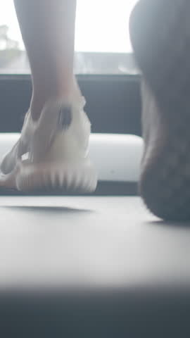 Vertical Screen : Young Asian guy feet in sneakers exercise running on treadmill fat burning workout in fitness class. Sportsman recreational activity, doing cardio training, people working out.
