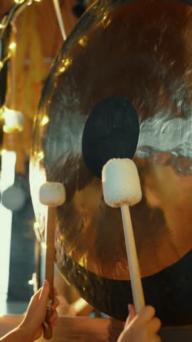 Person playing large gong with mallets