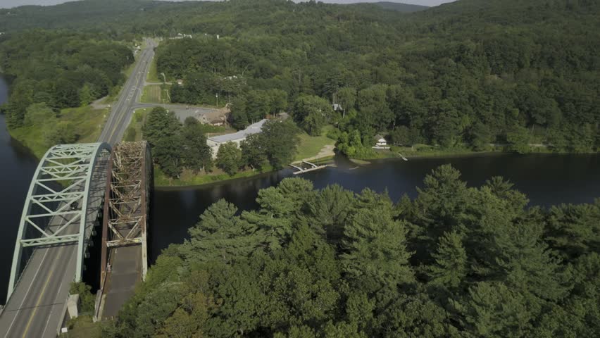 Drone flies east from Vermont over Connecticut River next to United States Navy Seabees Bridge to New Hampshire on summer afternoon
