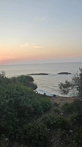 Sunset over the Mediterranean Sea in El Tarf, Algeria. A breathtaking view overlooking a sandy beach where people are setting up camp for the night. Watch as the sun dips below the horizon.