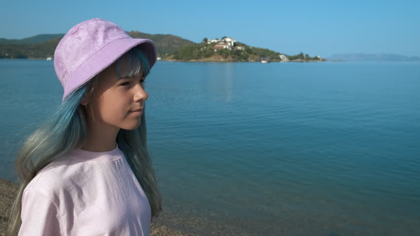 Cute girl in a hat on the background of a calm blue sea